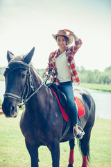 Girl riding a horse in the farm in cowboy style. Sport, happiness, hobby concept