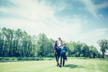 Fototapeta premium Couple riding a horse in the farm in cowboy style. Sport, happiness, hobby concept