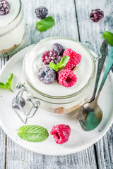 Recipe ideas for summer diet breakfast, healthy morning dessert Cheesecake in portioned jars with summer berries - raspberry, blueberry, blackberry. On wooden background copy space