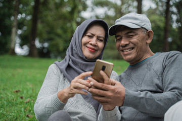 old man and woman using mobile phone in the park