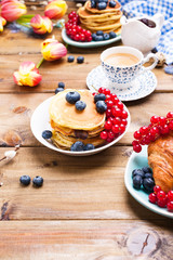 Fresh morning coffee and pastries homemade for breakfast. Pancakes with berries for a romantic breakfast and spring flowers. The concept for Easter and home comfort.