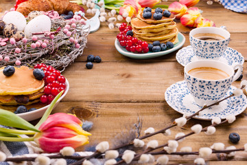 Fresh morning coffee and pastries homemade for breakfast. Pancakes with berries for a romantic breakfast and spring flowers. The concept for Easter and home comfort.