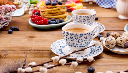 Obraz na płótnie Canvas Fresh morning coffee and pastries homemade for breakfast. Pancakes with berries for a romantic breakfast and spring flowers. The concept for Easter and home comfort.