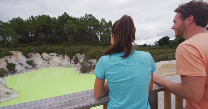 New Zealand travel tourists looking at colorful green pond. Tourist couple enjoying famous attraction on North Island, geothermal pools at Waiotapu, Rotorua, New Zealand.