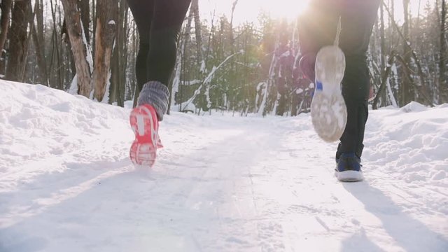 Young man and woman running in winter forest. Morning. Snow flies out from under the soles