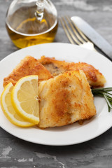fried cod fish with lemon on white plate