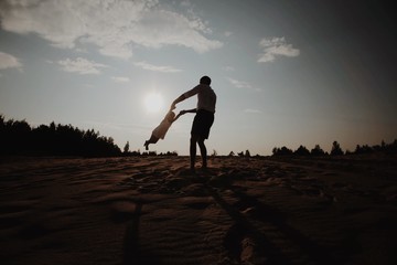 A father throws his infant child into the air. People silhouettes