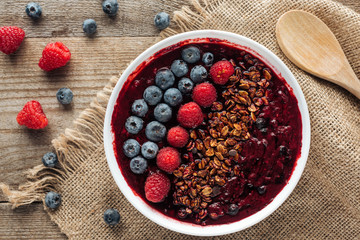 top view of fresh organic smoothie bowl with berries and granola on sackcloth