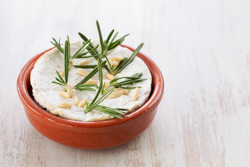 cheese camembert with nuts and rosemary in ceramic dish