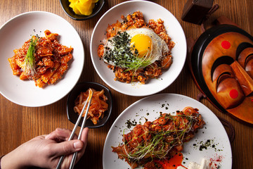 Male hand holds Chinese food with chopsticks. Top view on traditional chinese cuisine. Restaurant, food menu, recipe, cafe concept. Lifestyle food Korean cuisine. Local food. Free copy space