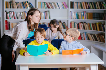 Education, elementary school, learning and people concept. Three children reading open books in...