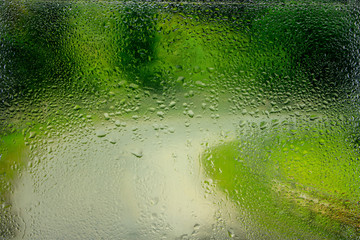 Water droplets on a window pane with beautiful defocused scenery outside.