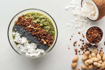 top view of fresh green smoothie bowl with ingredients on white background