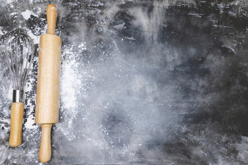 dough preparation recipe bread. equipment accessories baking ingredients bakery cooking. Egg whisk,rolling pin and flour. flat lay on table dark background. Top view, copy space.