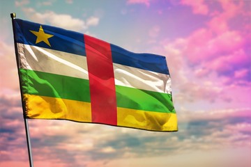 Fluttering Central African Republic flag on colorful cloudy sky background. Prosperity concept.