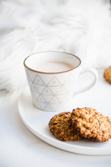 Cozy weekend breakfast with fur blanket, cup of coffee and cookies on ceramic tray