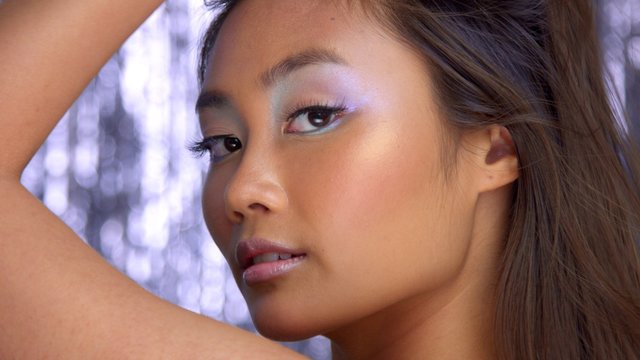 thai asian model in studio with silver rain disco background and party makeup Blowing hai