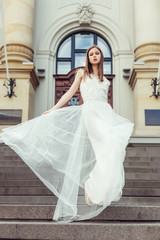 Gorgeous elegant caucasian young lady posing outdoors in old town in fashionable wedding dress. Beauty, fashion, vogue concept