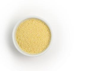 Dry couscous in white ceramic bowl isolated on grey. Spilled couscous. Healthcare