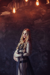 Fototapeta premium Pregnant woman in jeans holds hands on belly on a black background. Pregnancy, maternity, preparation and expectation concept. Close up, copy space, indoors. Beautiful tender mood photo of pregnancy