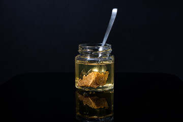 truffle mushroom in a jar of honey on a black background. Minimalism in composition. Luxury food. Free space for text.