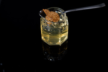 truffle mushroom in a jar of honey on a black background. Minimalism in composition. Luxury food. Free space for text.