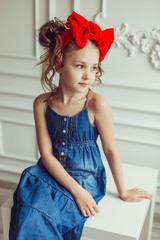 Fashionable close up portrait of young teen girl in jeans dress with red bow