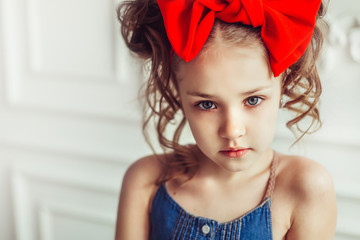 Fashionable close up portrait of young teen girl in jeans dress with red bow