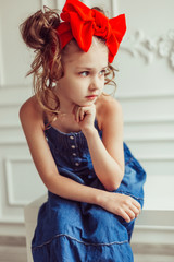 Fashionable close up portrait of young teen girl in jeans dress with red bow