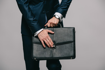 cropped view of businessman opening briefcase isolated on grey