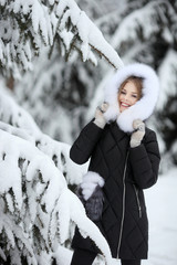 portrait of smiling woman in winter clothing looking at camera in snowy park