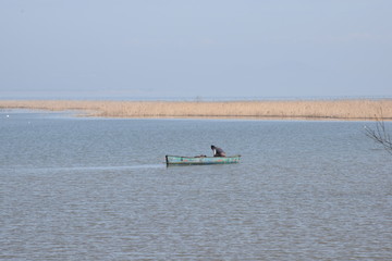 calm lake with blue sky and a small fishing boat far away