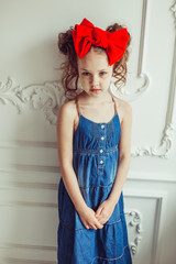 Fashionable close up portrait of young teen girl in jeans dress with red bow