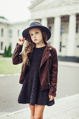 Outdoor portrait of teenage girl in stylish look, in black hat posing outdoors in park