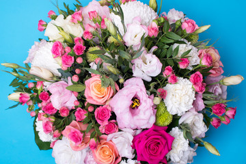 beautiful floral arrangement, pink and yellow rose, pink eustoma, green and pink chrysanthemum, white carnation, pink dahlia on a blue, turquoise background with space for text.