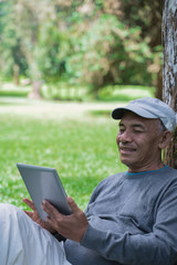 Fototapeta premium senior old man using tablet pc in the park