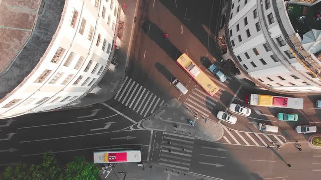 Smooth lift drone above the intersection with the camera down. Traffic at dawn long shadows. Lifting the camera, overlooking the city