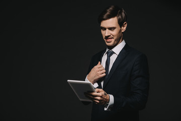 smiling businessman holding digital tablet in hands isolated on black