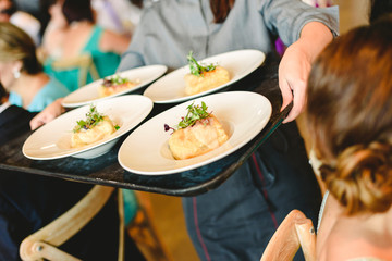 Waiters serving plates of appetizers to diners and guests to a party.
