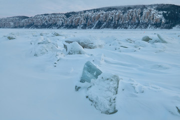 Fototapeta na wymiar Winter landscape in blue tones with ridged ice on the frozen Lena river at sunset in the Natural Park Lenskie Stolby (Lena Pillars), Yakutia, Russia
