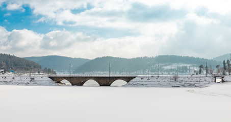 frozen lake schluchsee with bridge and blue sky with clouds in the black forest
