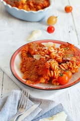 Plate with baked pasta with tomato sauce and mozzarella cheese