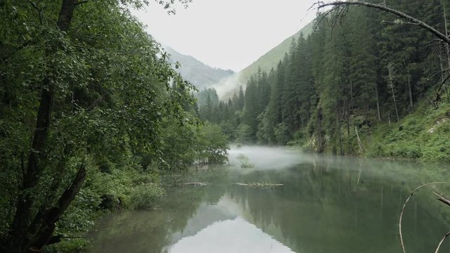 Mountain lake, foggy peaceful atmosphere. Place for alpine hiking, walking, swimming, sports and leisure activities. Wading water level. Day stabilized v-log shot