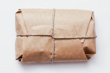 Box parcel wrapped in brown craft paper   tied hemp cord on white background. 