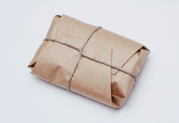 Box parcel wrapped in brown craft paper   tied hemp cord on white background. 
