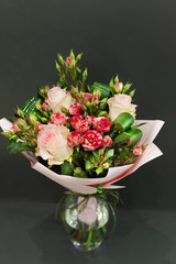 Bright bouquet of bright colors in paper packaging against a gray background.