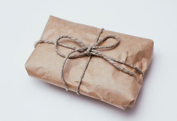 Box parcel wrapped in brown craft paper   tied hemp cord on white background. 