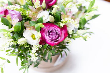 An impressive bouquet of bright flowers in a colored hat box on a white background