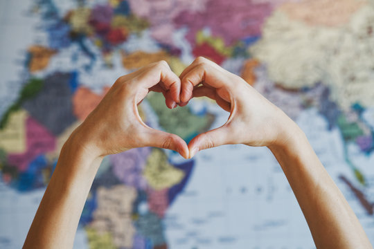 female hands in form of heart against world map background 
