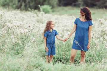Fototapeta premium Happy mother and daughter outdoors in the summer having fun together. Motherhood, love, family, happiness concept